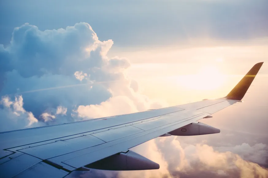 Airplane wings above the clouds during sunrise